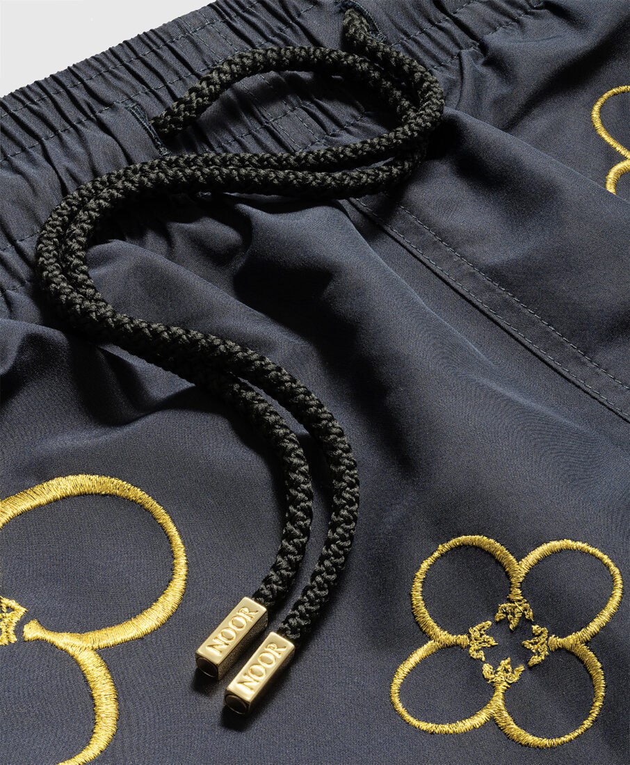 Detail of swim shorts with gold embroidery, professionally photographed in Italy by Inlet Studio.